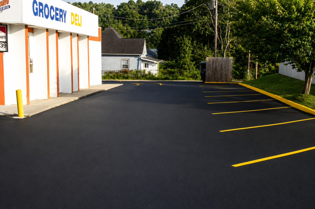 A wide view of a freshly paved commercial parking lot with yellow curb paint and parking lines.